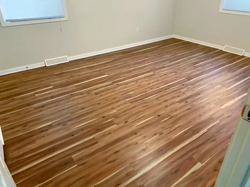 Wood-look luxury vinyl plank flooring with strong grain variation installed wall to wall in an empty bedroom of an Olathe, Kansas home