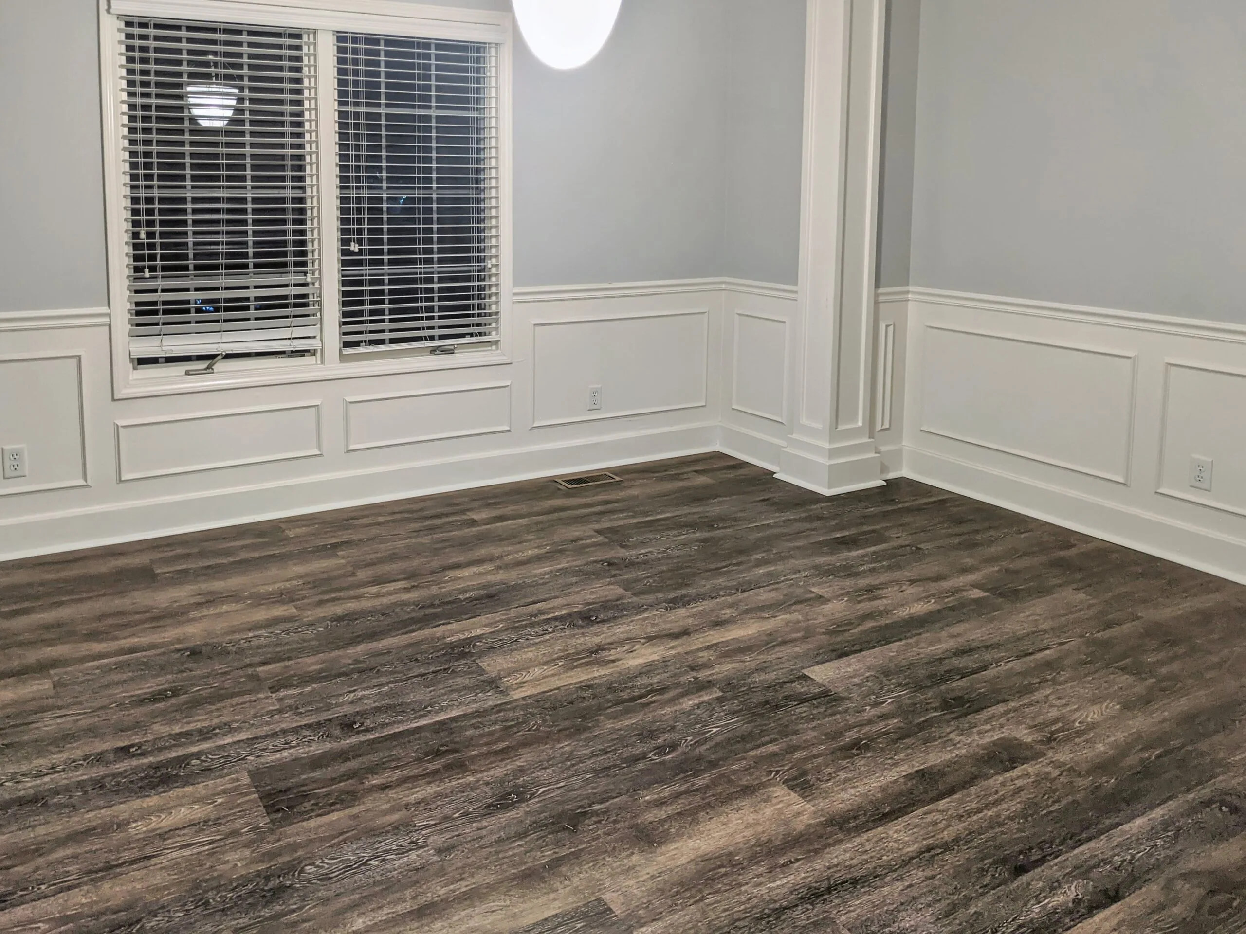 Weathered-oak look luxury vinyl plank flooring installed wall to wall in a dining room with white wainscoting, on a Midwest Flooring Company project in the Kansas City area