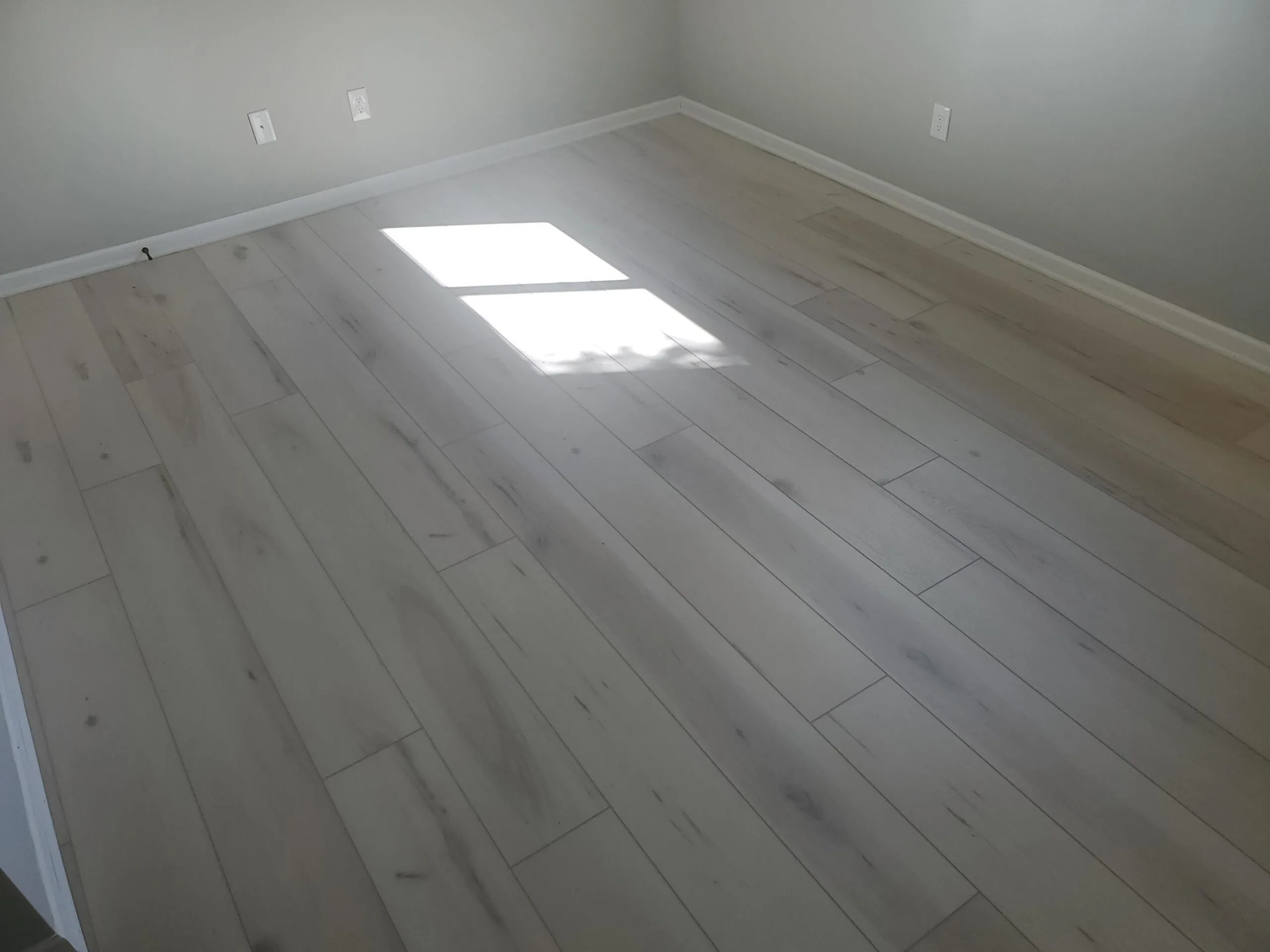 Light whitewashed wide-plank waterproof luxury vinyl flooring installed wall to wall in a lower level in Lenexa, Kansas