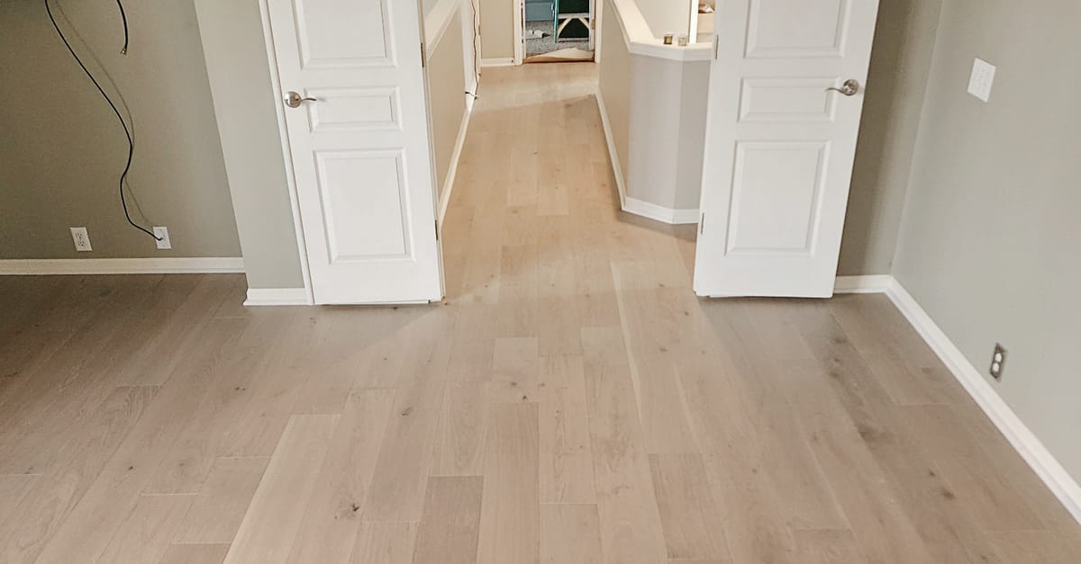 Light oak hardwood running without a threshold strip from an upstairs room through open double doors into the hallway of an Overland Park home